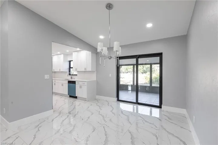 Unfurnished dining area with recessed lighting, marble finish floor, a sink, baseboards, and a chandelier