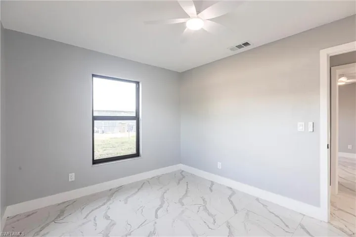Unfurnished room with visible vents, marble finish floor, baseboards, and ceiling fan