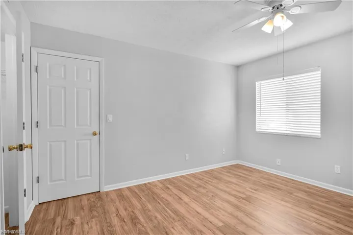 Empty room with ceiling fan, light wood-type flooring, and a textured ceiling