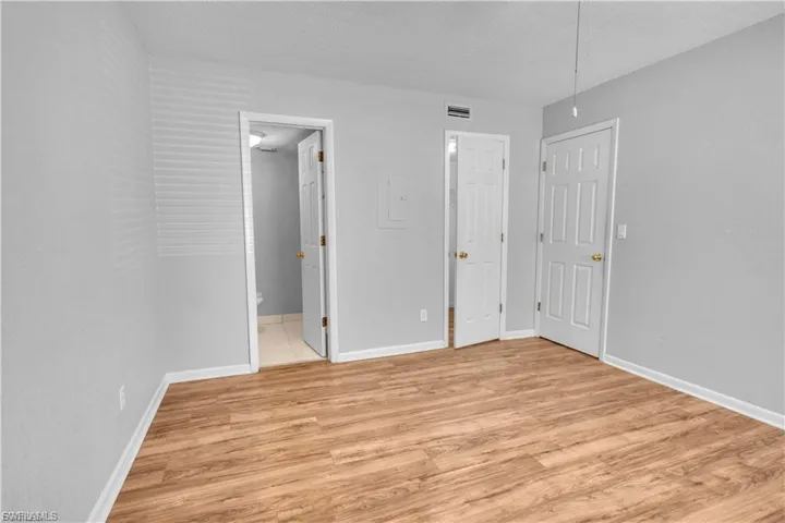 Unfurnished bedroom featuring light wood-type flooring, a textured ceiling, a ceiling fan, and connected bathroom
