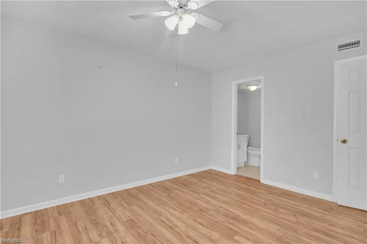 Unfurnished bedroom featuring light wood-style flooring, a ceiling fan, and ensuite bathroom