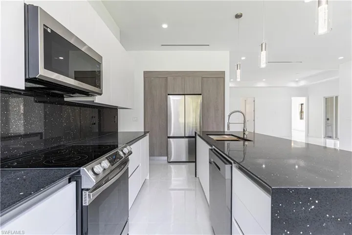 Kitchen featuring appliances with stainless steel finishes, dark stone countertops, modern cabinets, white cabinets, and recessed lighting