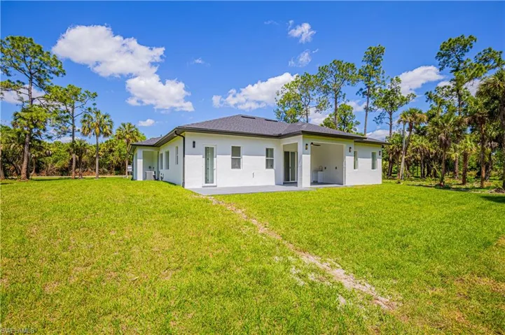 Rear view of property featuring a patio area, stucco siding, and a lawn