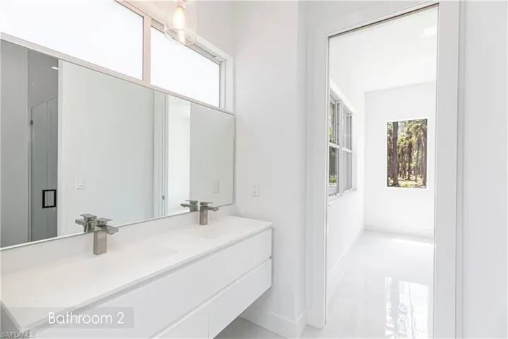 Full bath with double vanity, a sink, and baseboards