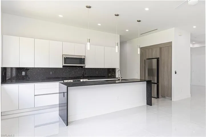 Kitchen with a sink, dark countertops, modern cabinets, and stainless steel appliances