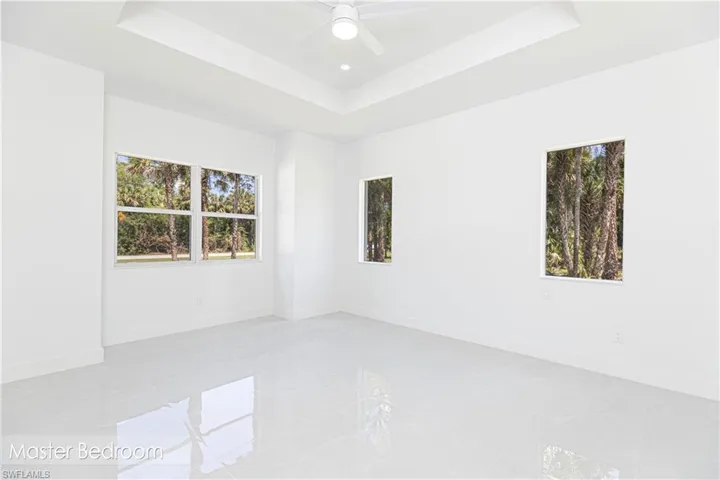 Unfurnished room featuring ceiling fan, baseboards, and a raised ceiling