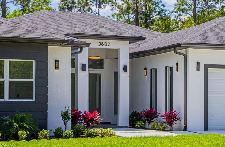 Doorway to property featuring stucco siding, roof with shingles, and a garage