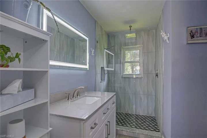Bathroom featuring vanity, a shower stall, and a textured wall