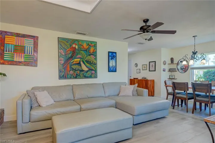 Living room featuring light wood-style flooring, a chandelier, and a ceiling fan