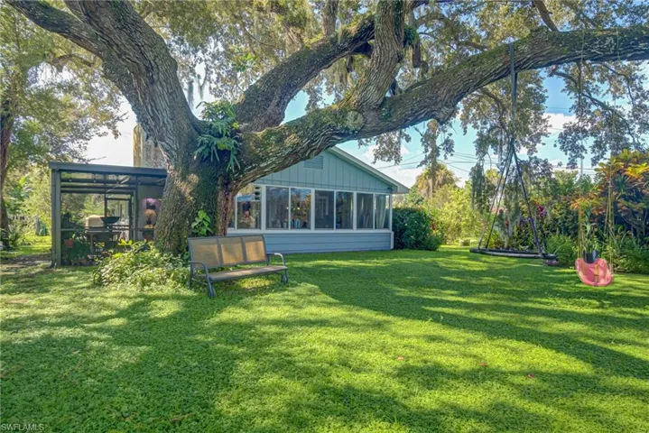 Rear view of property with a sunroom, board and batten siding, and a lawn