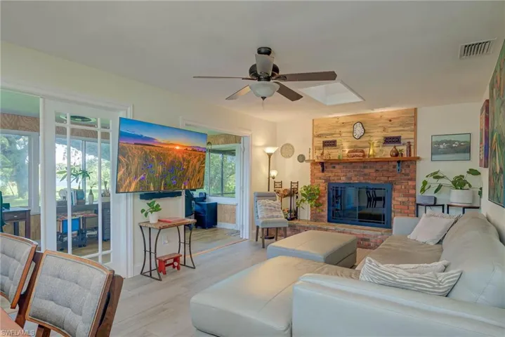 Living area with wood finished floors, a fireplace, and a ceiling fan