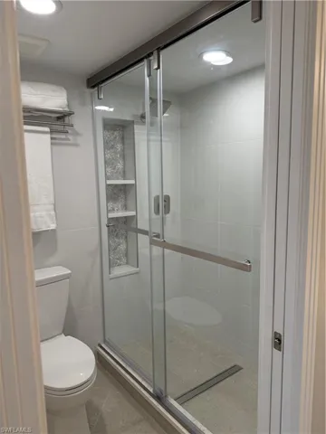 Full bathroom featuring a shower stall, tile patterned floors, and tile walls