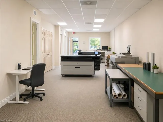 Spacious commercial room featuring neutral-toned carpet flooring and a suspended acoustic tile ceiling with integrated lighting
