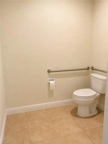 2nd Private water closet featuring a standard toilet, grab bars, and light-toned floor tile