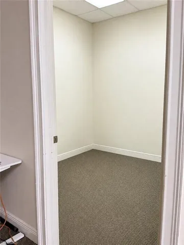 Compact interior space featuring neutral wall paint, textured carpeting, and white baseboards