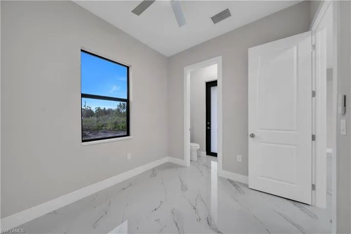 Unfurnished bedroom with light marble finish floors and ceiling fan