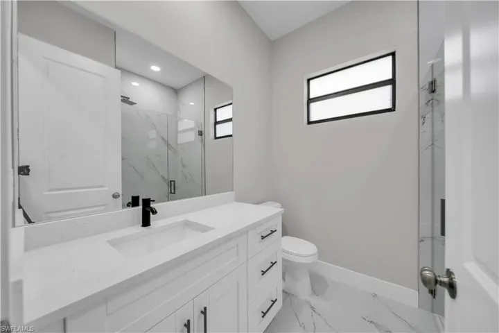 Full bathroom featuring vanity, a marble finish shower, and light marble finish flooring