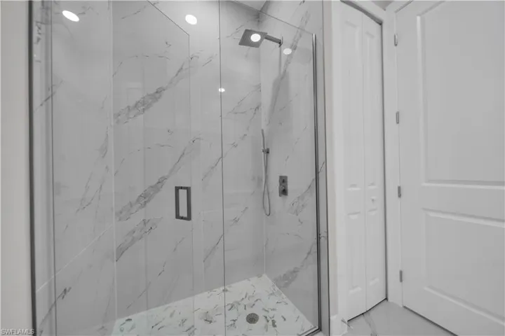 Bathroom featuring a marble finish shower and a closet