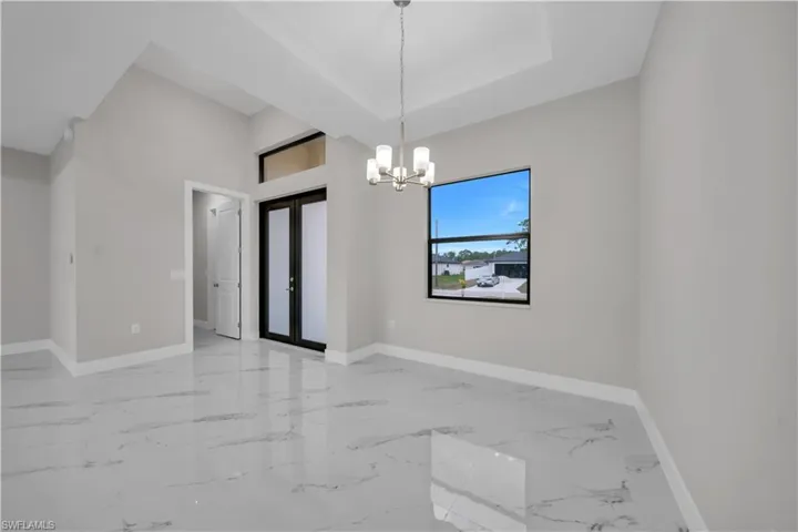 Unfurnished room featuring baseboards and a chandelier