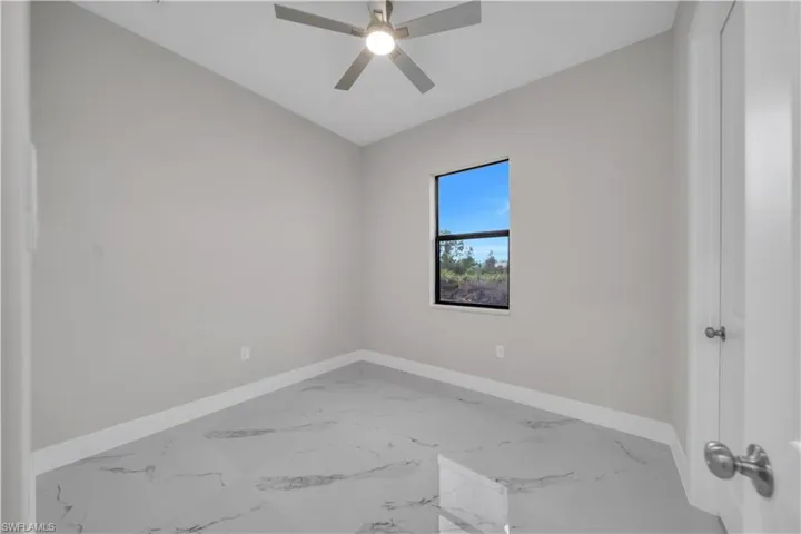 Unfurnished room with marble finish floors and a ceiling fan