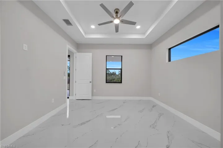 Spare room featuring recessed lighting, marble tiled floors, ceiling fan, and a tray ceiling