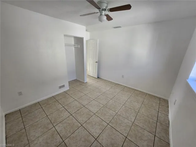 Unfurnished bedroom featuring a closet, light tile flooring, and ceiling fan