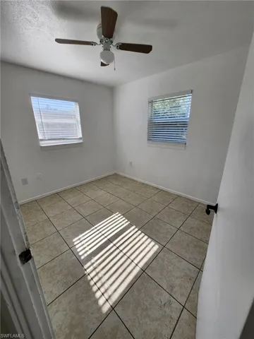Tiled spare room featuring ceiling fan