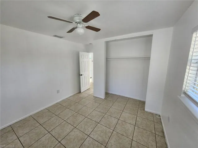 Unfurnished bedroom with a closet, ceiling fan, and light tile floors