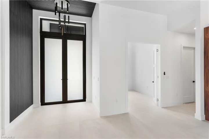 FOYER lined w/ ACOUSTIC PANELING, designer's lights, and impact resistant frosted double doors.
