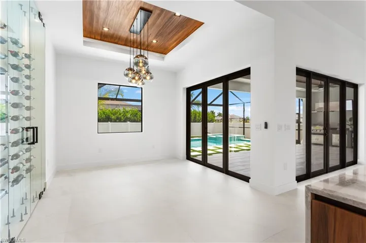 Enjoy MEMORABLE FORMAL DINING in dining room w/ DESIGNER LAMPS descending from FLAT WOODEN OVERHEAD CEILING, wide doors to lanai & large PICTURE WINDOW overlooking POOL/SPA.