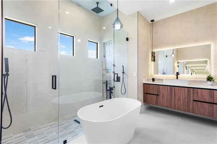 CUSTOM VANITIES w/ VESSEL SINKS above natural stone countertops & under-cabinet lights, elevating the bathroom experience to new heights of REFINEMENT & INDULGENCE.