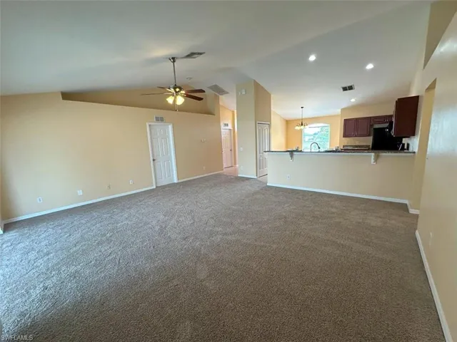 Unfurnished living room featuring a ceiling fan, lofted ceiling, carpet flooring, baseboards, and recessed lighting