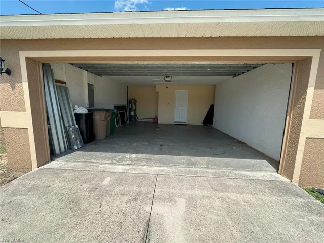 View of parking with driveway, an attached garage, and electric water heater