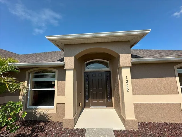 Entrance to property featuring stucco siding and a shingled roof