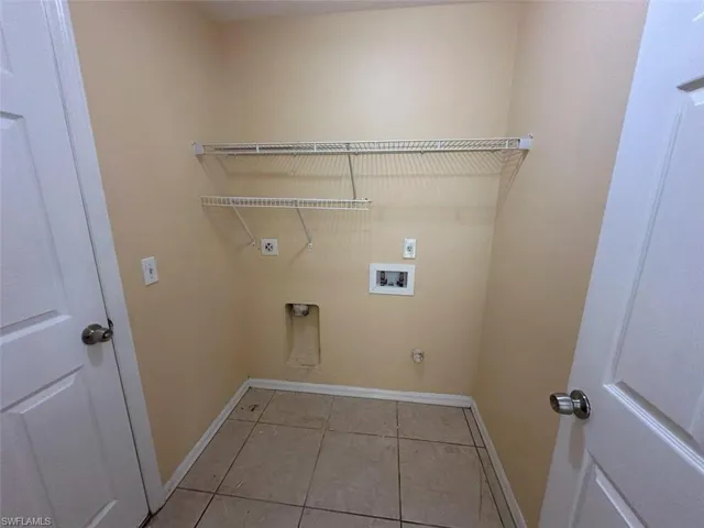 Laundry area featuring hookup for an electric dryer, baseboards, hookup for a washing machine, and light tile patterned floors