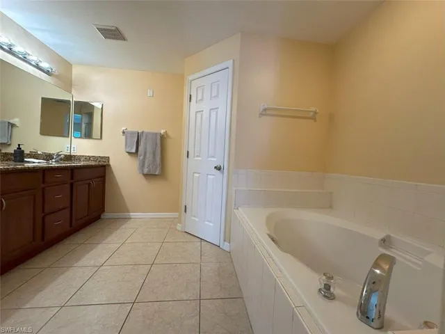 Master Bathroom with a garden tub, double vanity, tile patterned flooring, and baseboards