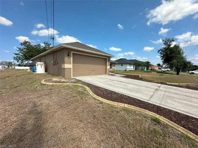 View of property exterior featuring an attached garage, driveway, stucco siding, and a lawn