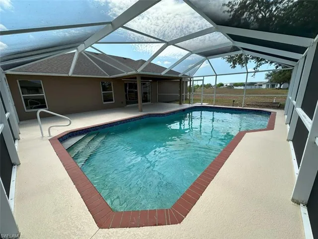 Outdoor pool with a patio area and glass enclosure