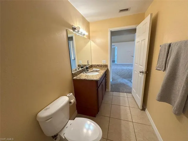 Full bathroom with vanity, tile patterned floors, toilet, and baseboards