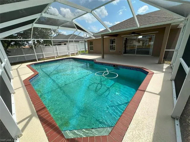 View of swimming pool with a patio, ceiling fan, fence, and glass enclosure