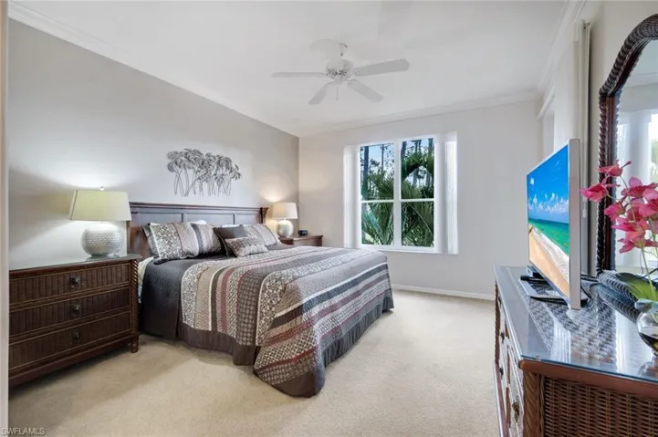 Bedroom featuring ornamental molding, light colored carpet, and a ceiling fan