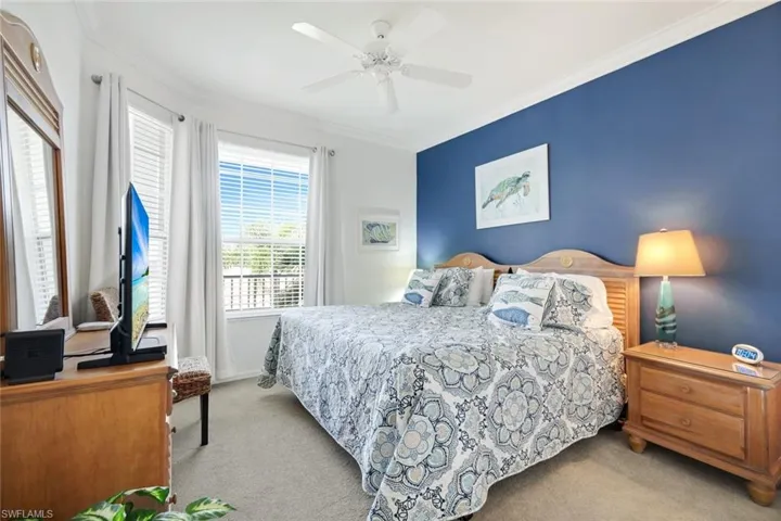 Bedroom with light colored carpet, ornamental molding, and a ceiling fan