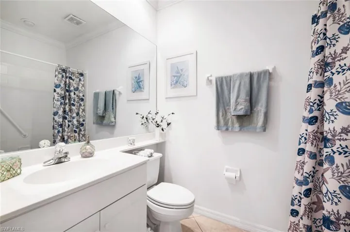 Bathroom featuring vanity, curtained shower, ornamental molding, and light tile patterned flooring