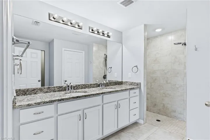 Unwind in the private primary bath featuring dual vanities, a walk-in shower, and a thoughtfully designed layout.