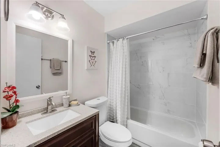 Full bathroom with toilet, vanity, and shower / bath combo with shower curtain