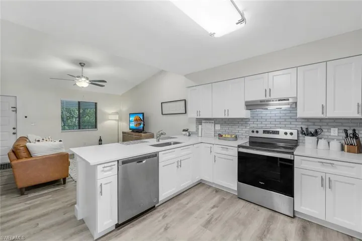 Kitchen with stainless steel appliances, under cabinet range hood, a sink, a peninsula, and open floor plan