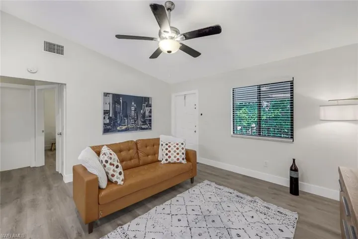 Living area with lofted ceiling, wood finished floors, baseboards, and a ceiling fan