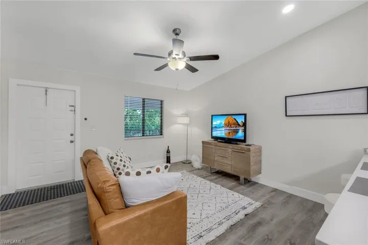 Living area with wood finished floors, a ceiling fan, vaulted ceiling, and baseboards