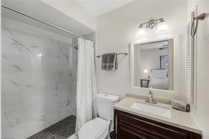 Full bathroom with tiled shower, vanity, and toilet