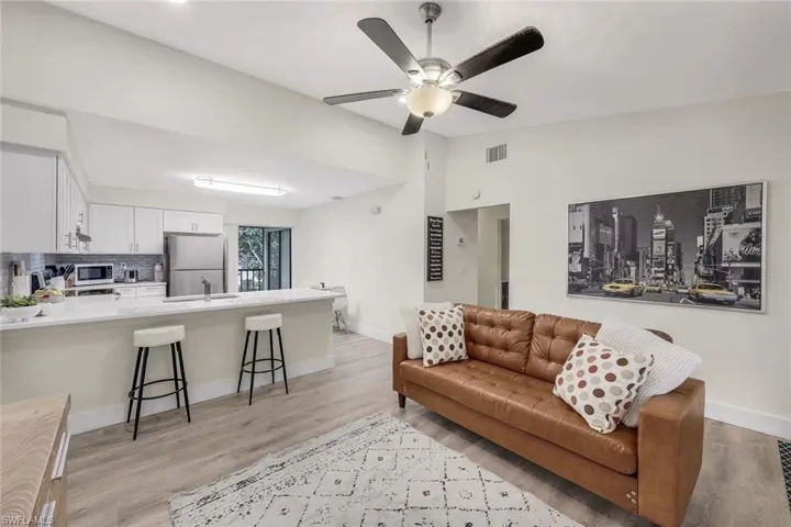 Living area featuring baseboards, light wood-style flooring, a ceiling fan, and vaulted ceiling